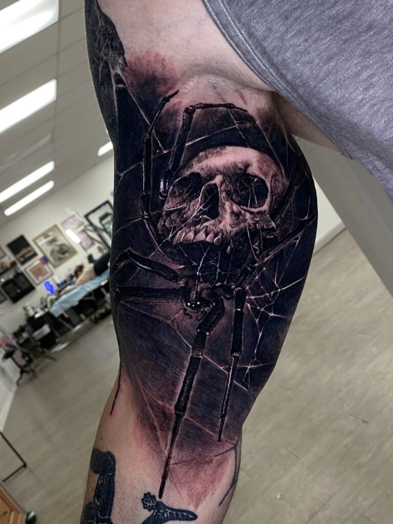 A Man’s Arm Adorned with a Striking Tattoo of a Spider Intertwined with a Skull