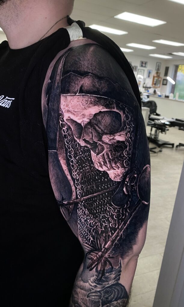 A Man Displays a Tattoo Featuring a Skull and a Sword on His Arm